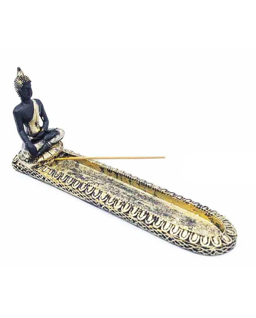 A decorative Buddha incense holder with a seated Buddha figure in black and gold at one end, a long oval tray with ornate gold detailing, and a single incense stick resting across the opening, shown on a plain white background.