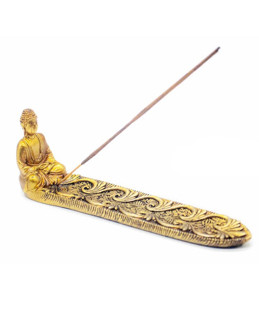 A gold-toned Buddha incense holder with an ornate engraved base and a single incense stick resting across the top, shown on a plain white background.
